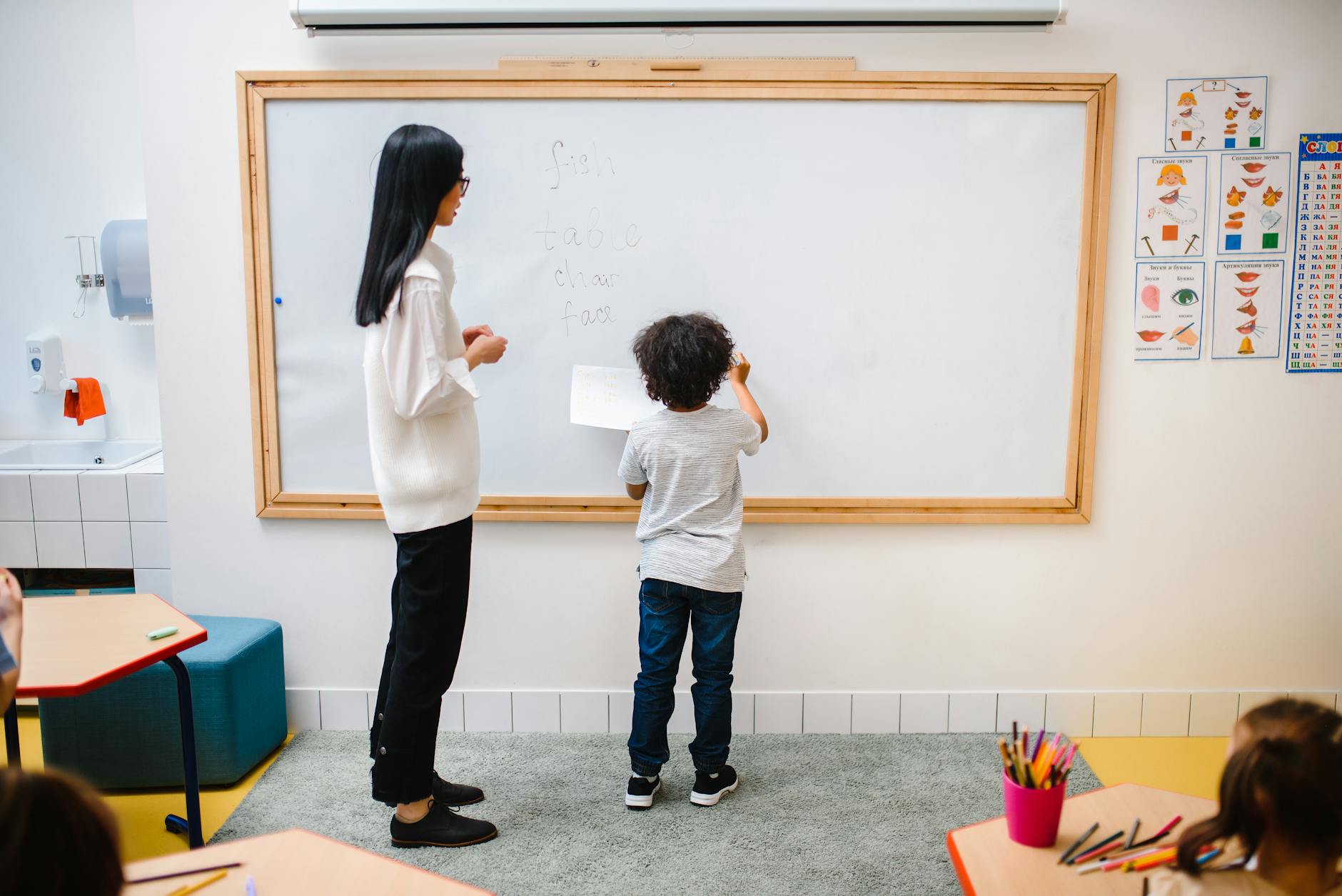femme et un garçon debout près d’un tableau blanc dans une salle de classe