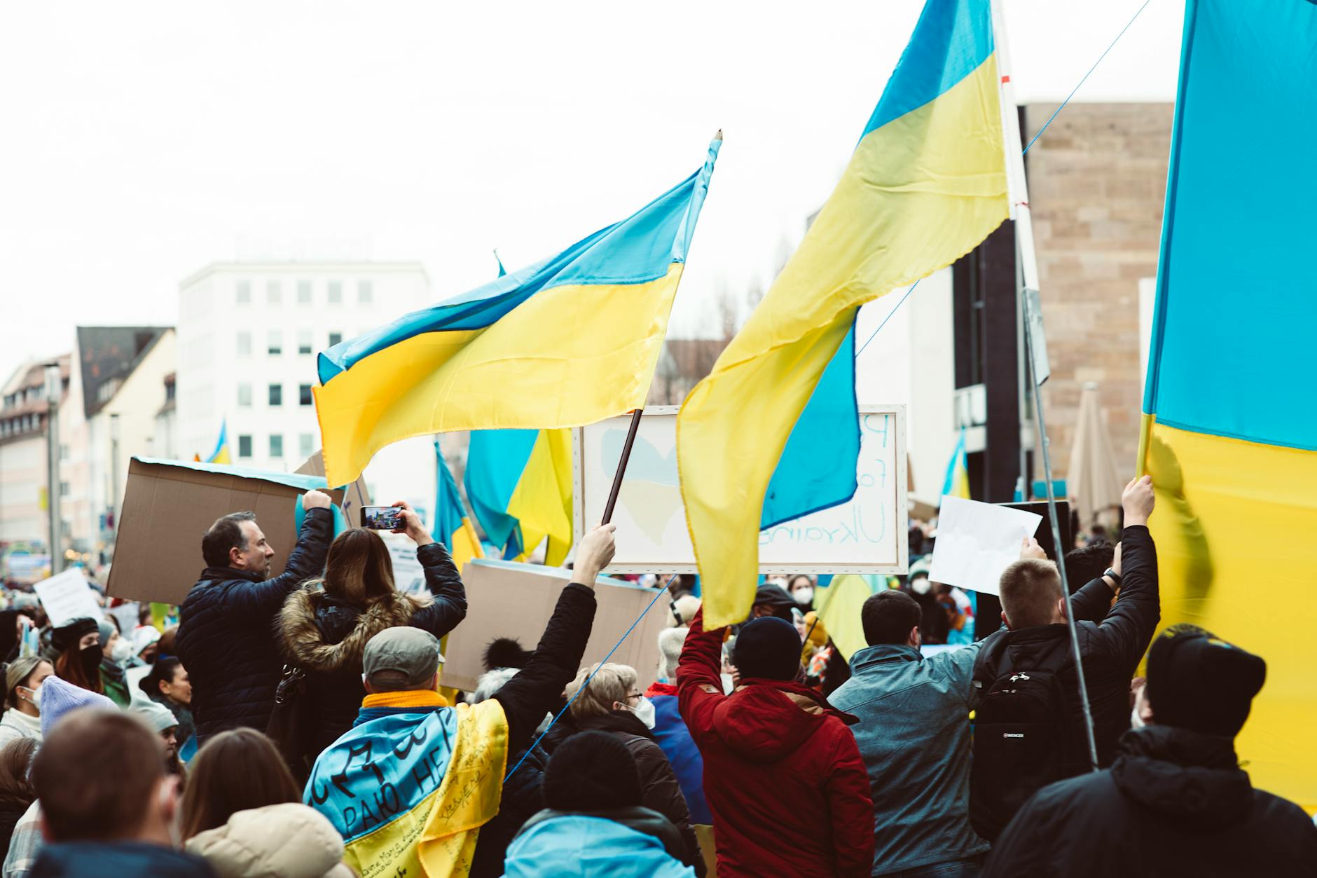 people gathering on street holding ukraine flags